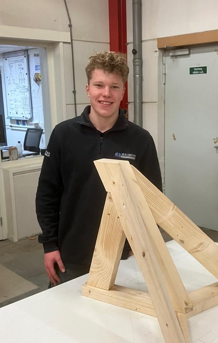 Leerling van Van Dinther staat voor een deel van een houten dakkapel