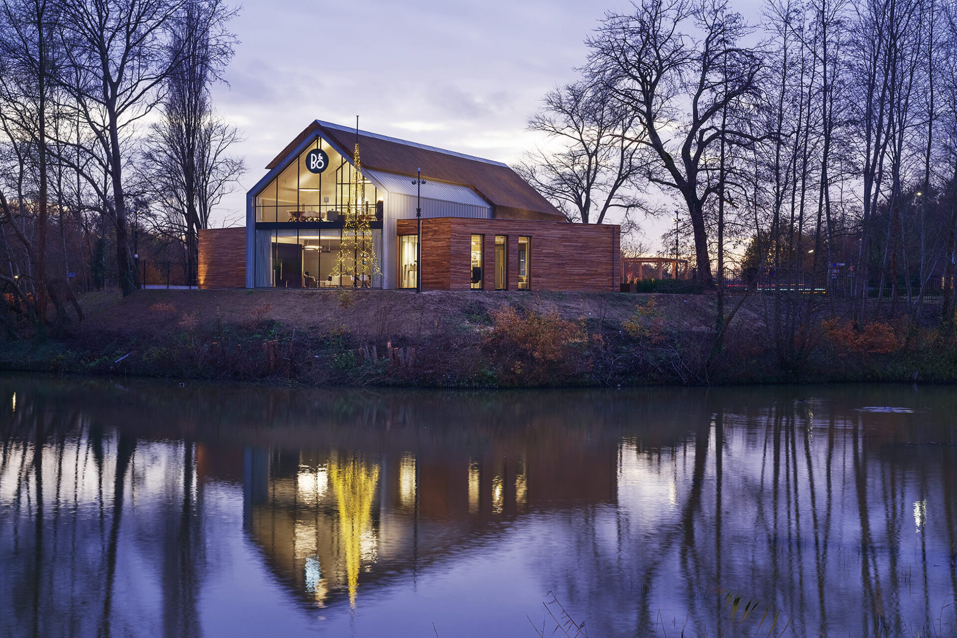 Achteraanzicht van het Bang en Olufsen Experience Center vanaf het water gefotografeerd in schemerlicht