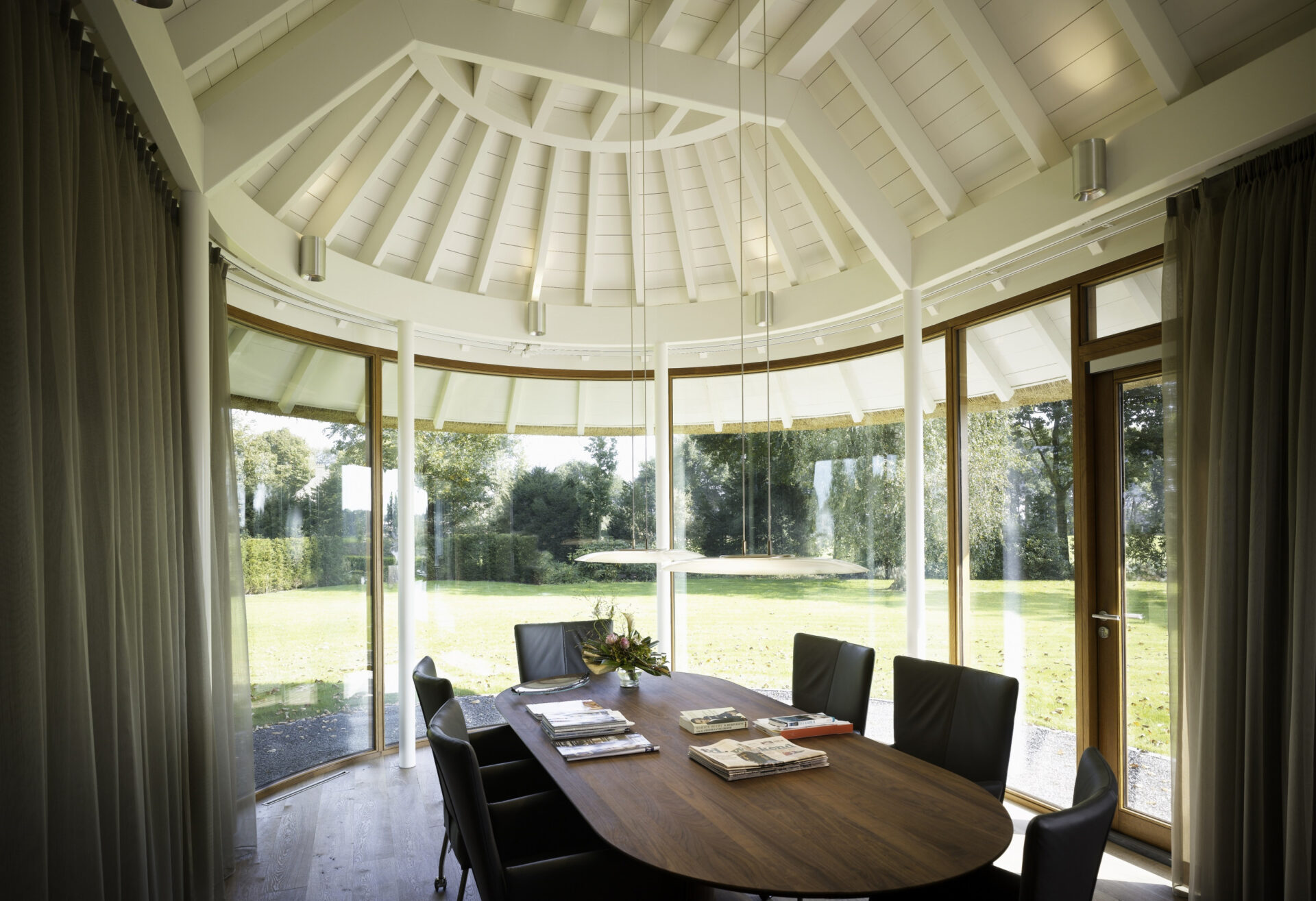 Aanbouw bij Landhuis Lage Wijst met ruimte om te zitten aan een lange donkerbruine tafel. Het plafond is met wit hout afgewerkt
