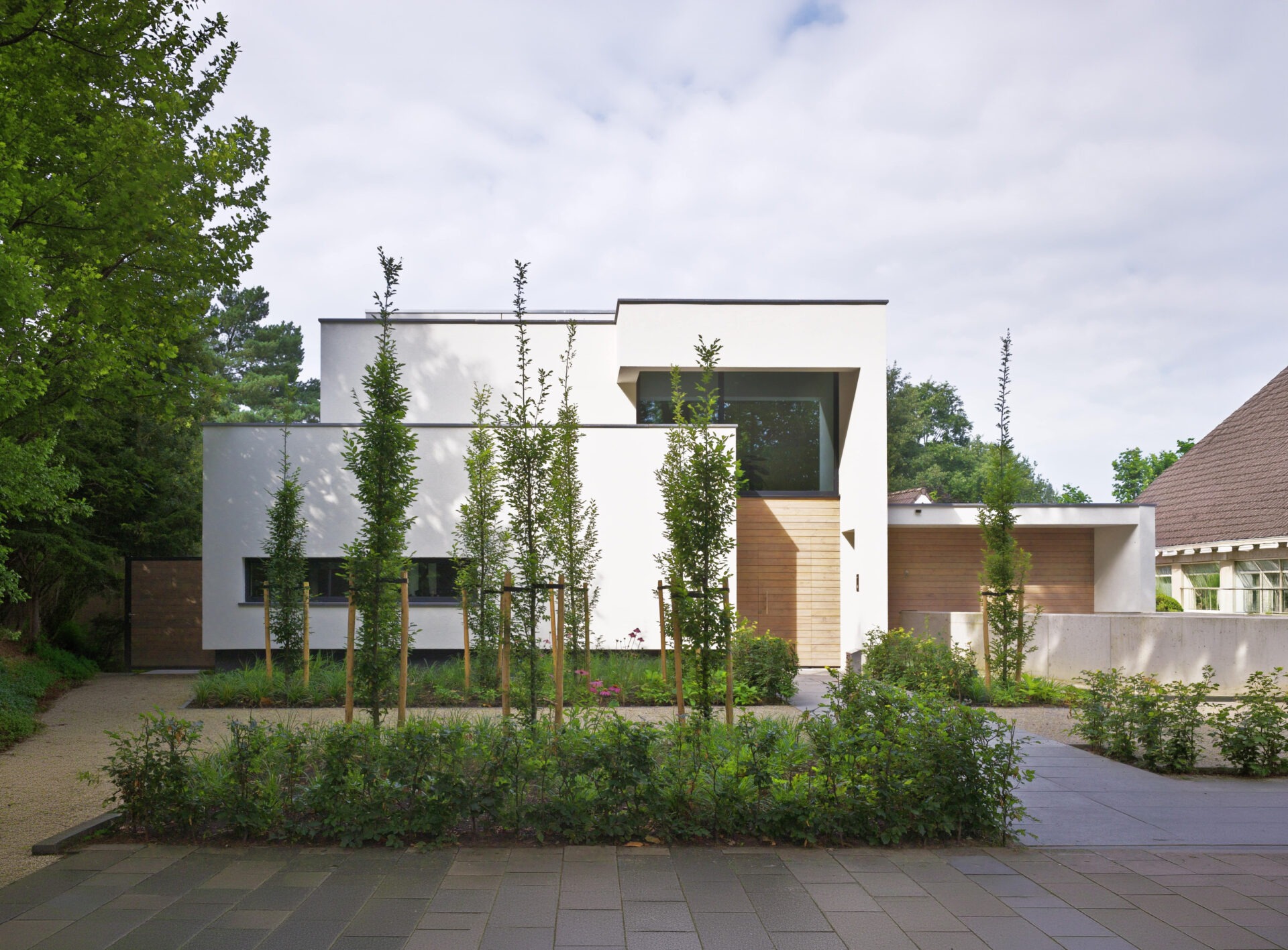 Vooraanzicht van villa bo. Het is een witte strakke moderne villa met een groene voortuin.