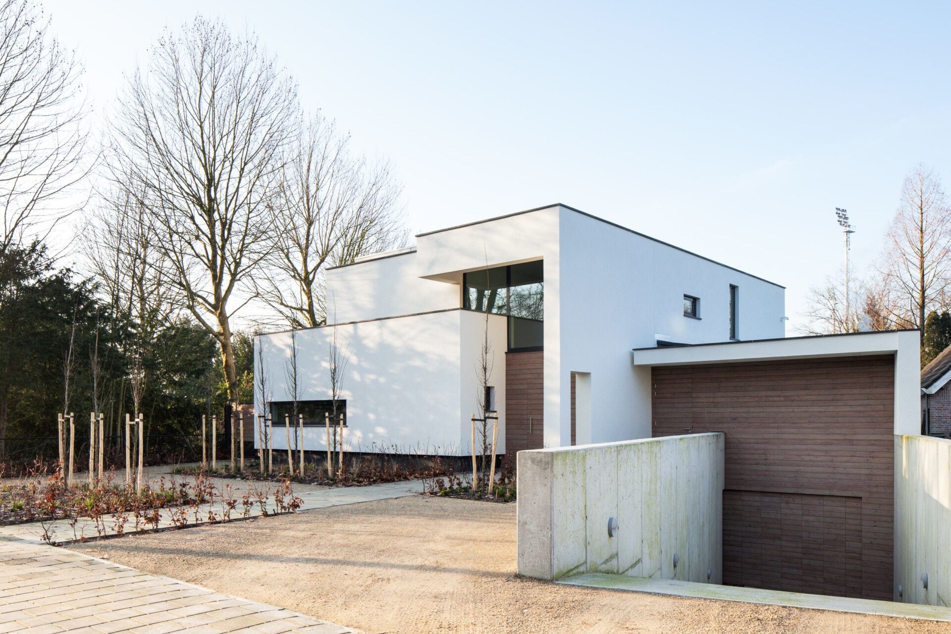 Vooraanzicht van villa bo. Het is een witte strakke moderne villa met een onderkelderde auto garage
