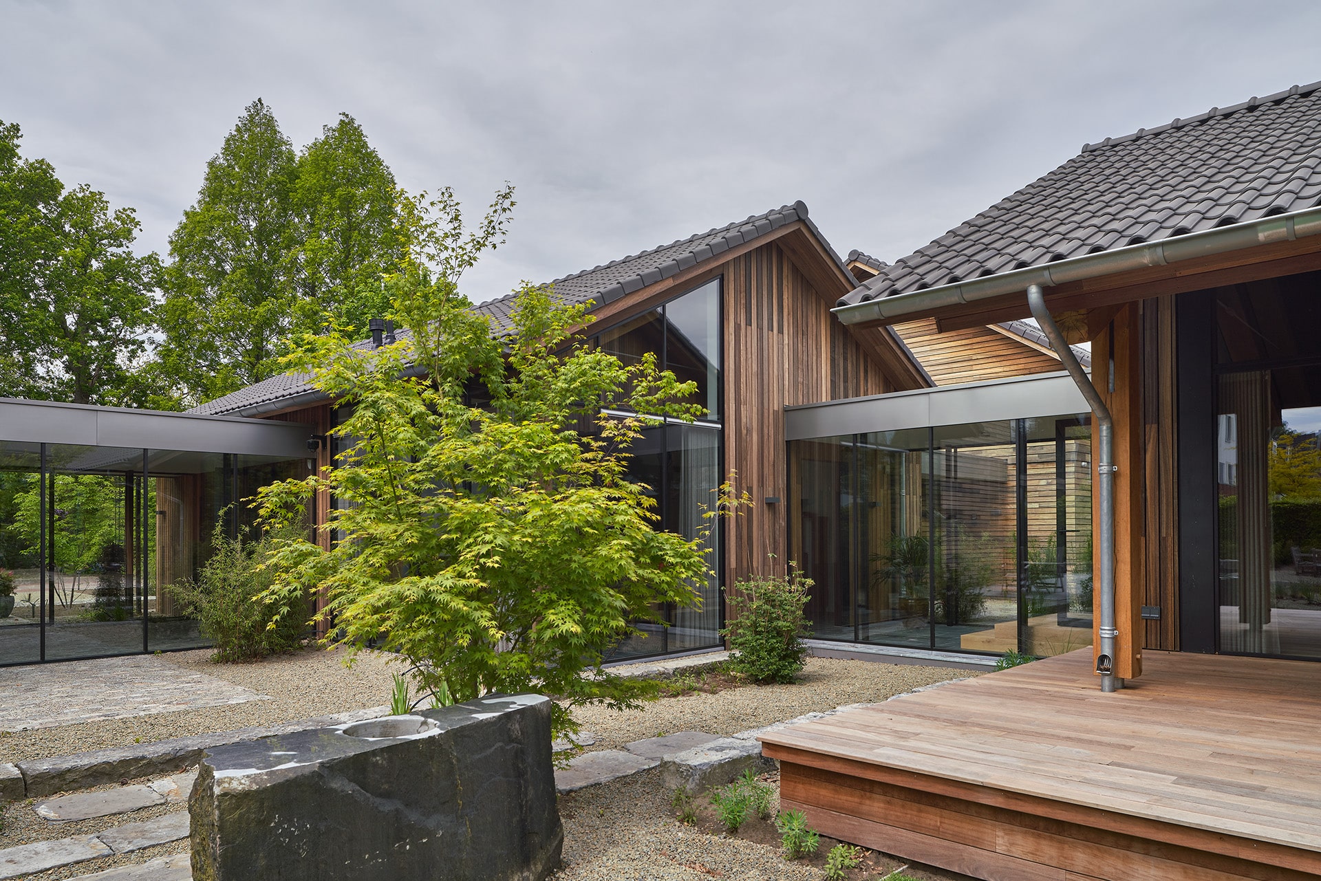 Zijaanzicht van Villa BV vanuit de tuin gezien. Op dekvoorgrond zie je een boom en een eikenhouten vlonder