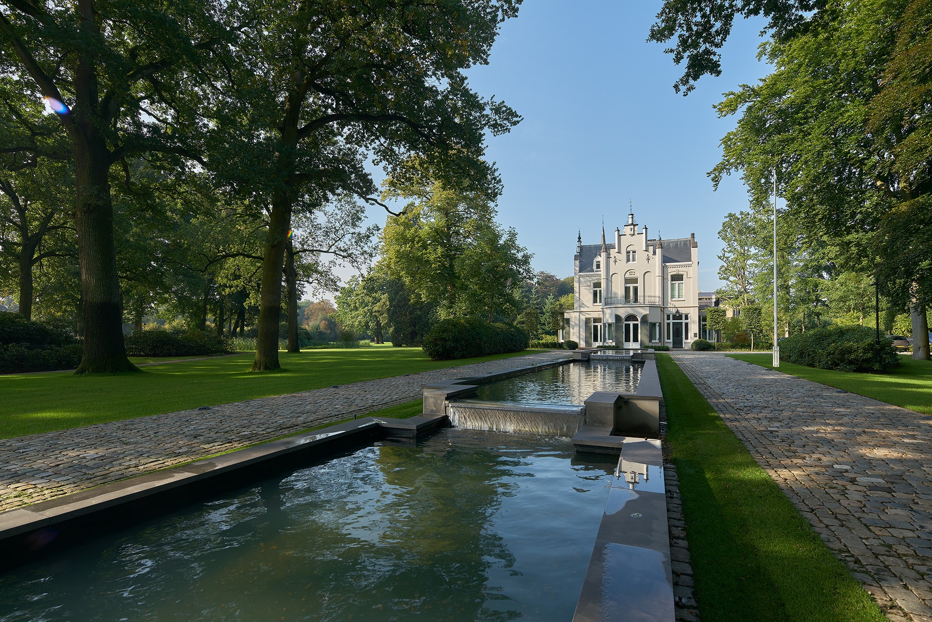 Vooraanzicht villa cv met een lange oprijlaan met een vijver in het midden