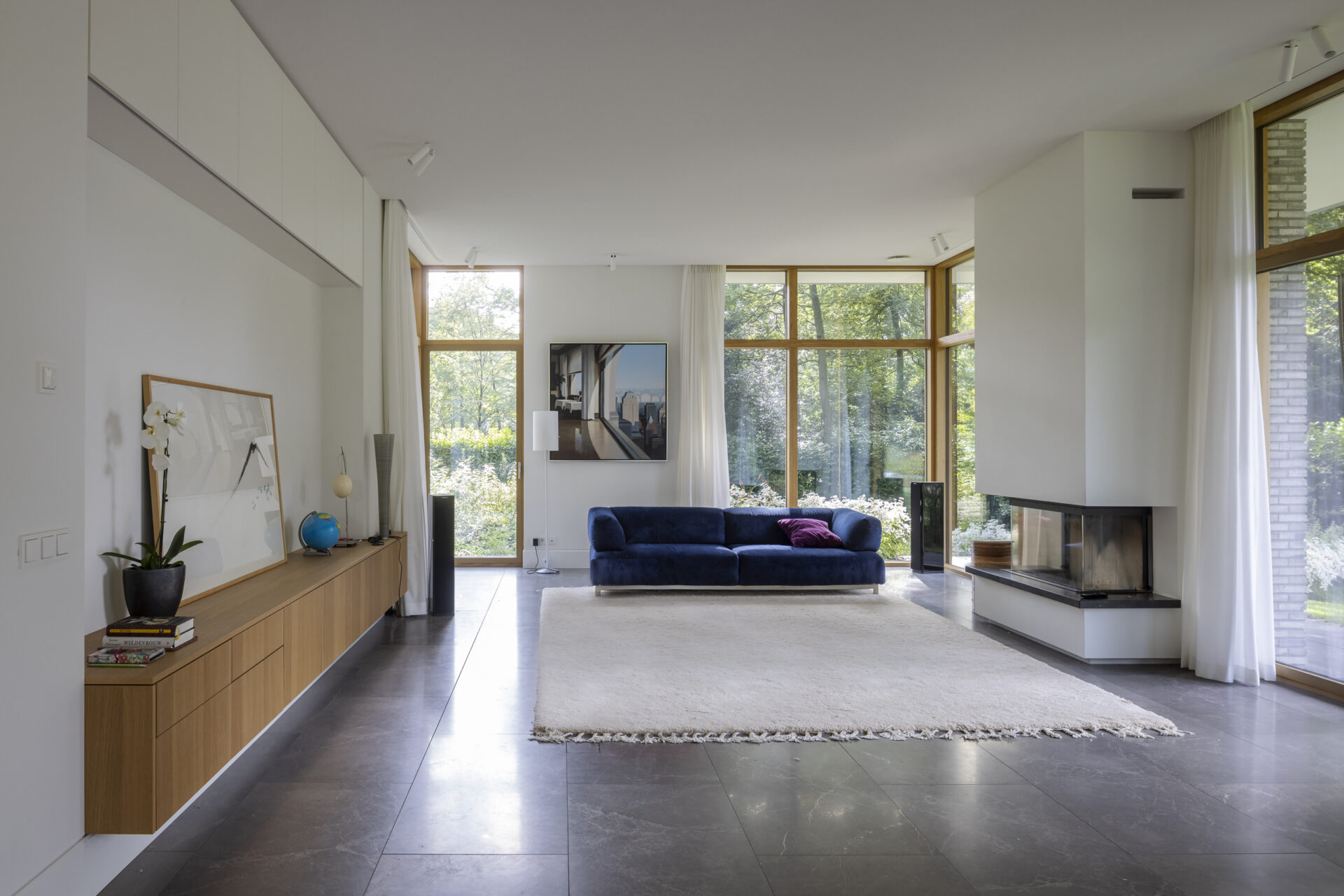 Woonkamer met blauwe bank en veel lichtinval