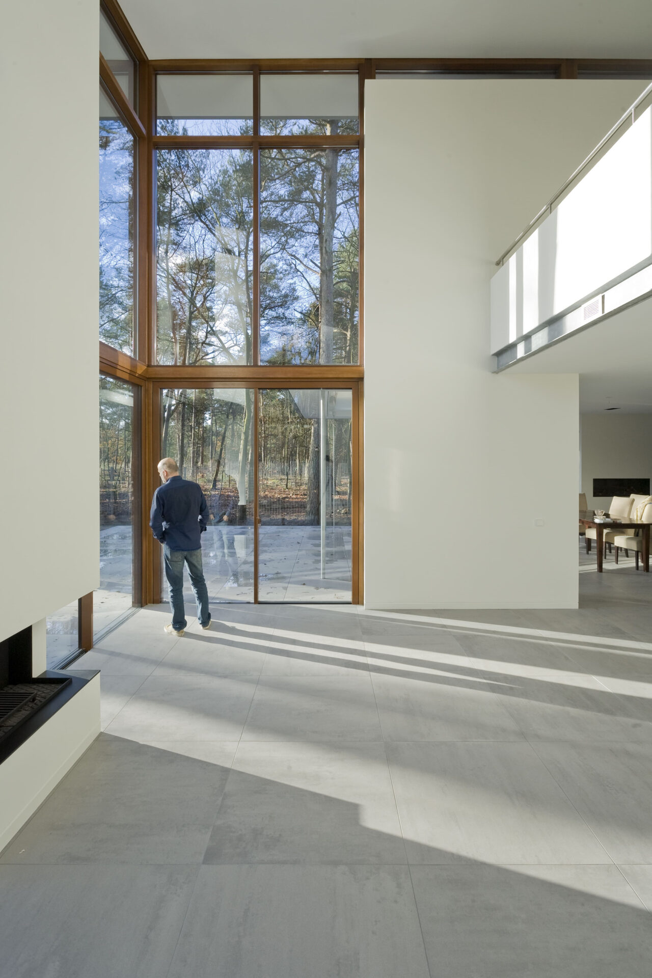 Binnenzijde van Villa Kerckebosch. Een man kijkt via de raampartijen naar de tuin