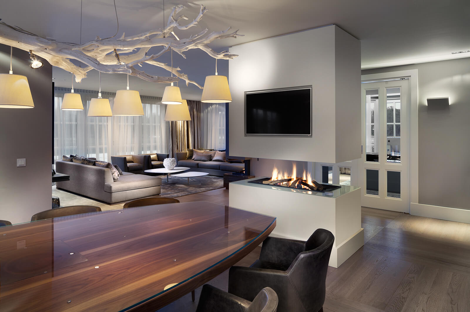 Woonkamer en keuken van Villa SL. Op de voorgrond een brandende haard en op de achtergrond een bank