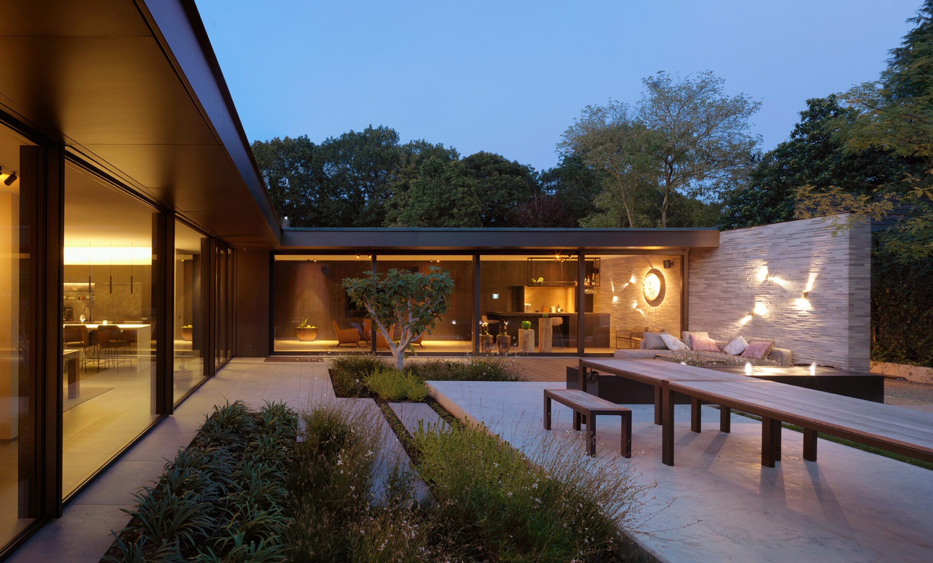 Achtertuin villa vdl met moderne sfeerverlichting en een lange tuintafel