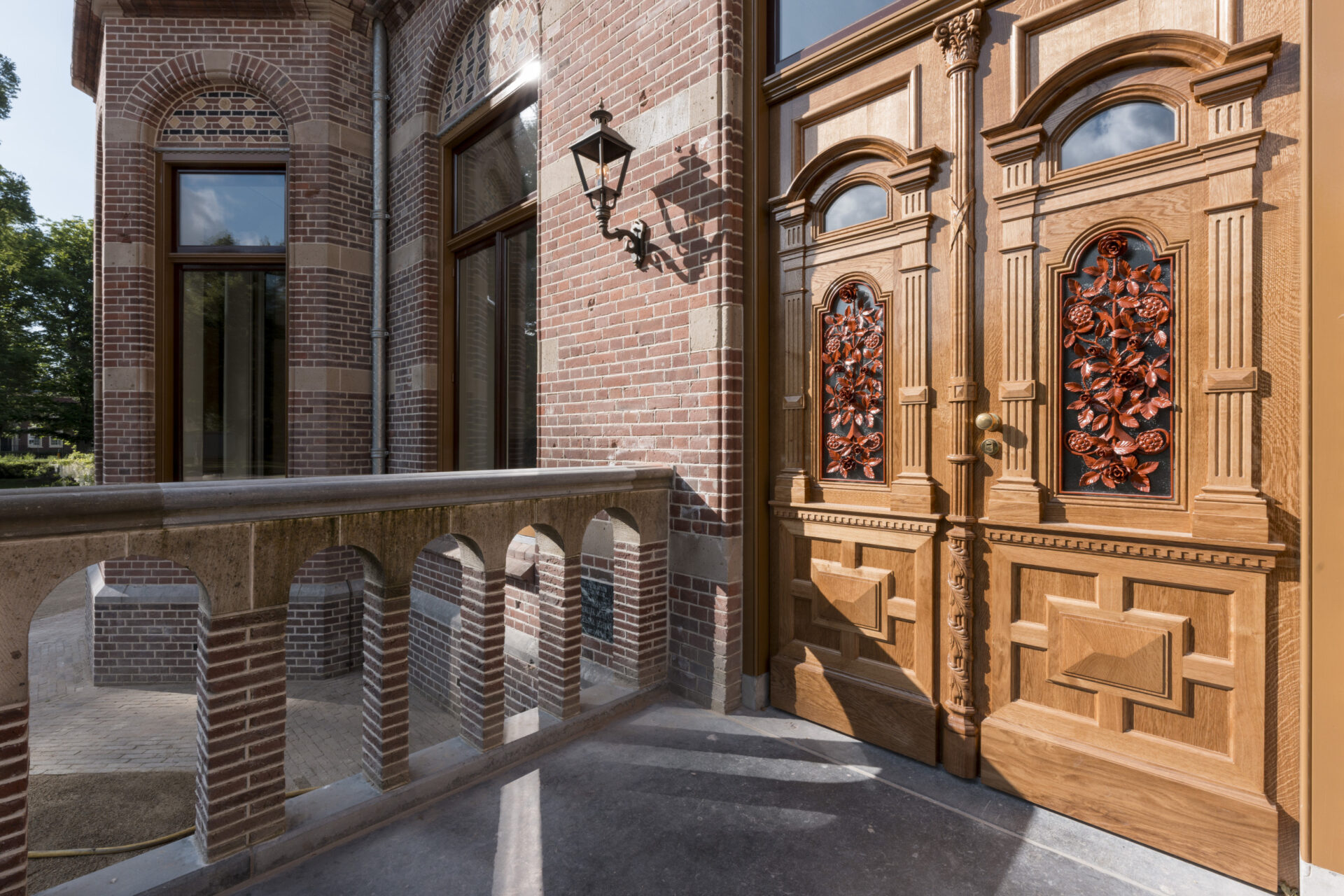 Houten deuren van Hoofdhuis Zionsburg met een bloemenraamwerk in rood oranje kleur