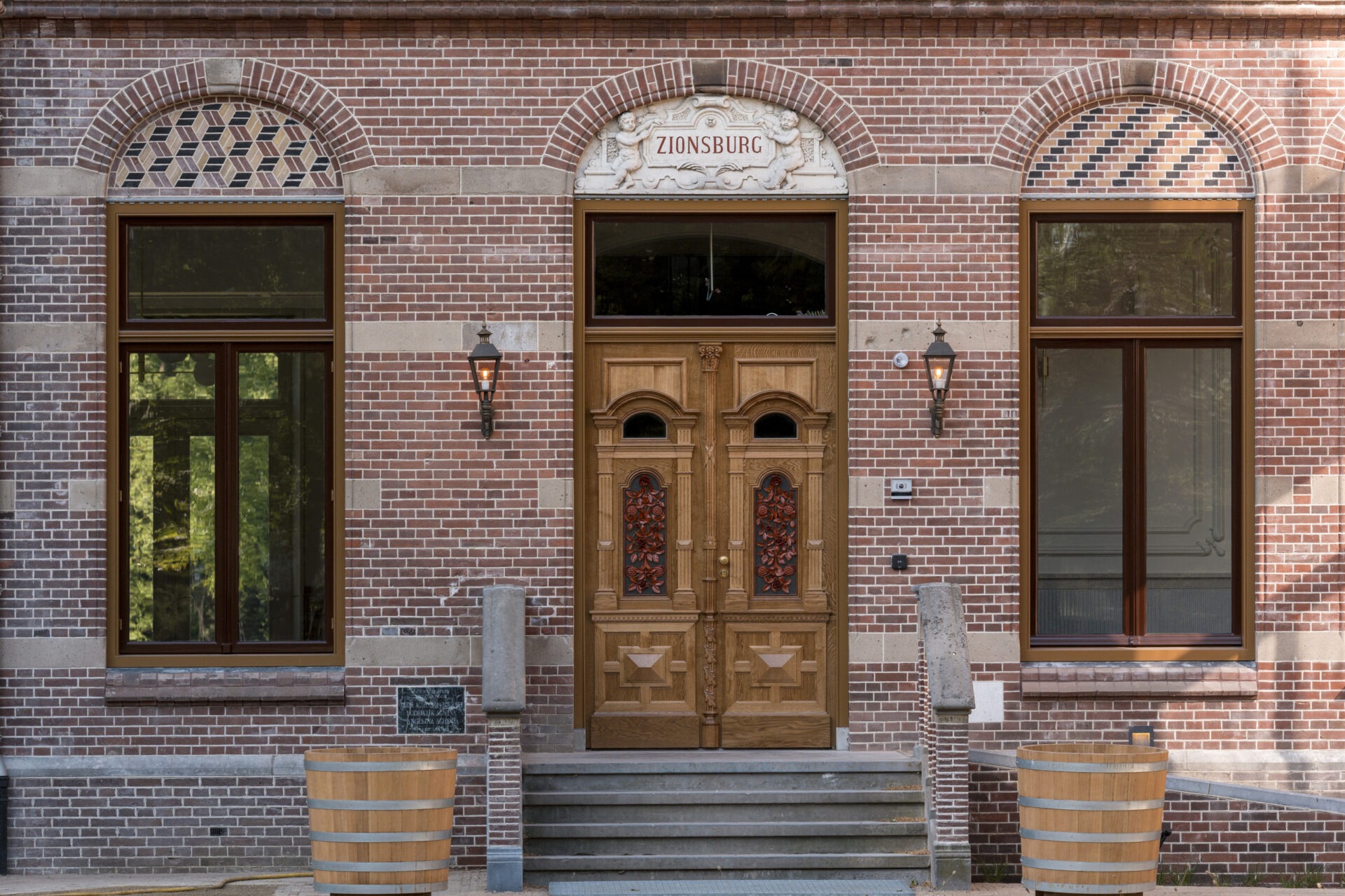 Voorzijde van de entree van Hoofdhuis Zionsburg met houten deuren met daarin een rood oranje raamwerk