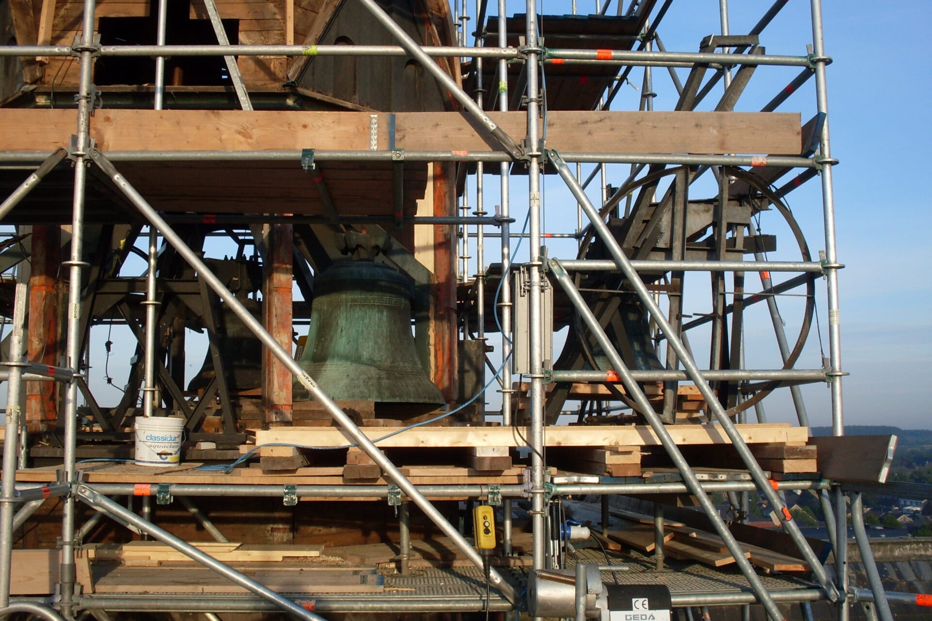Detailfoto van de toren van de R.K.H. Alphonsuskerk met klok in de steigers