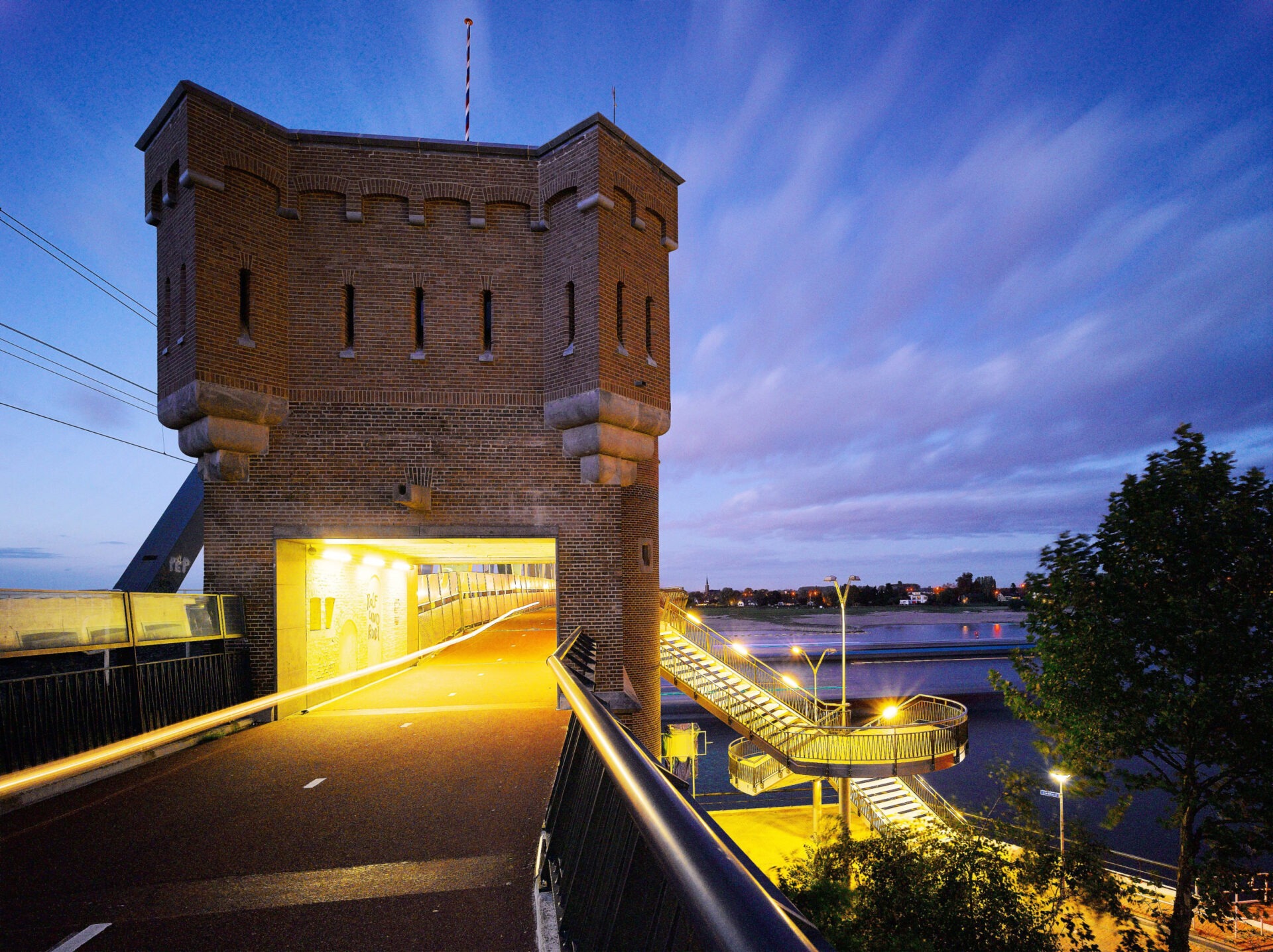 De doorgang bij het landhoofd van de spoorbrug in de avond