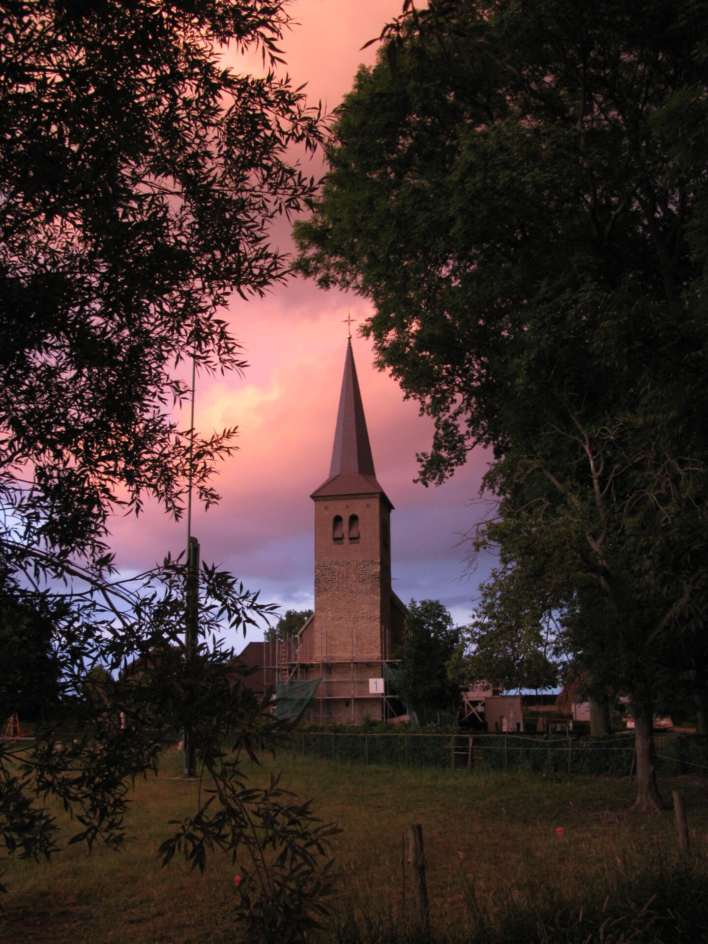 De toren van de Sint Jan de Doper kerk bij zonsondergang