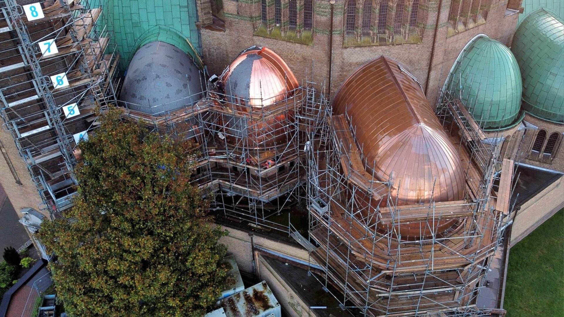 De koperkleurige en blauwe koepels van de Sint Janskerk tijdens de restauratiewerkzaamheden