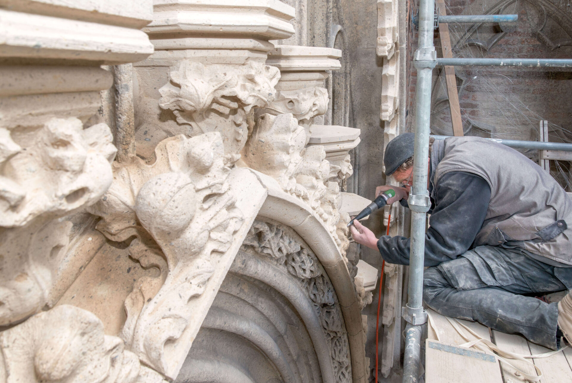 Detailfoto van een medewerker van Van Dinther tijdens restauratiewerkzaamheden aan de geveldecoratie van de Stevenskerk