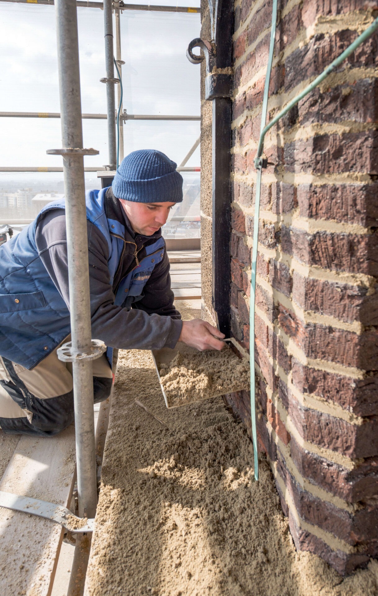 Medewerker van Van Dinther tijdens restauratiewerkzaamheden. De medewerker renoveert het voegwerk