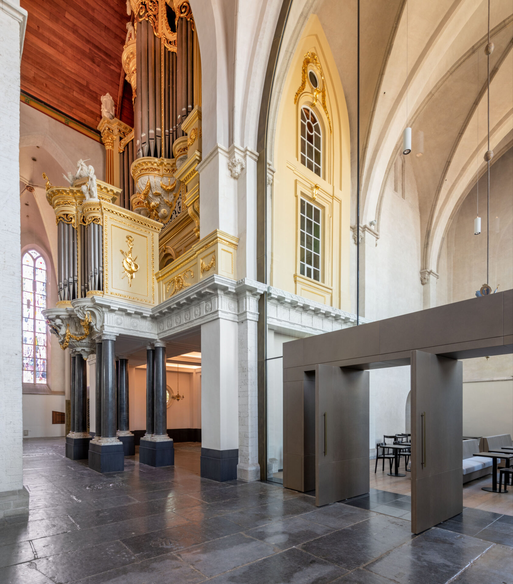 Binnenzijde van de Stevenskerk. Op de voorgrond een ruimte gescheiden door een glazen wand. Op de achtergrond het orgel