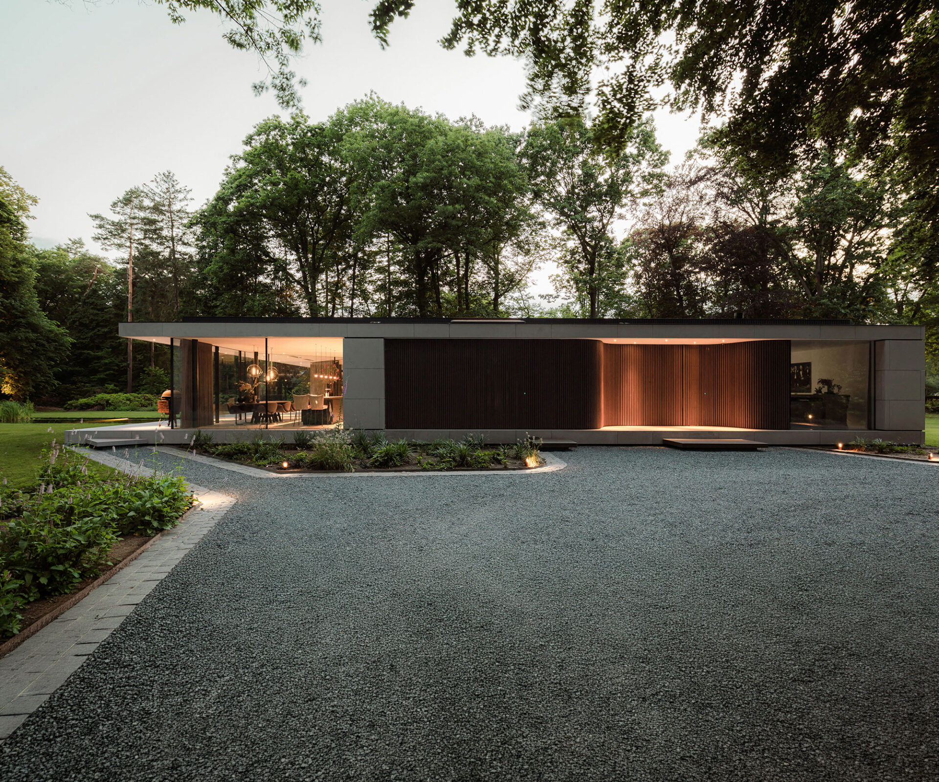 Paviljoen gelegen in een bosrijke omgeving met een grindpad.