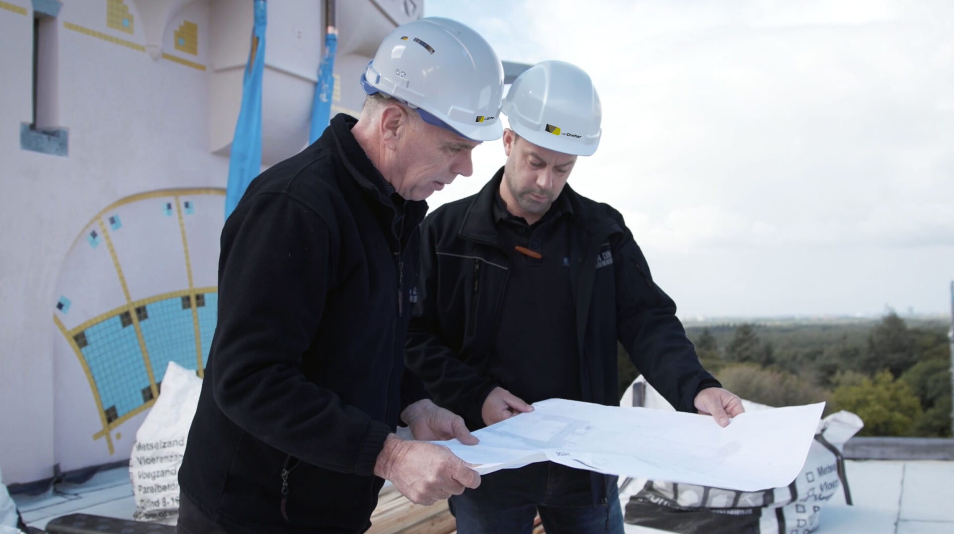 twee mannen met een werktekening in overleg met elkaar