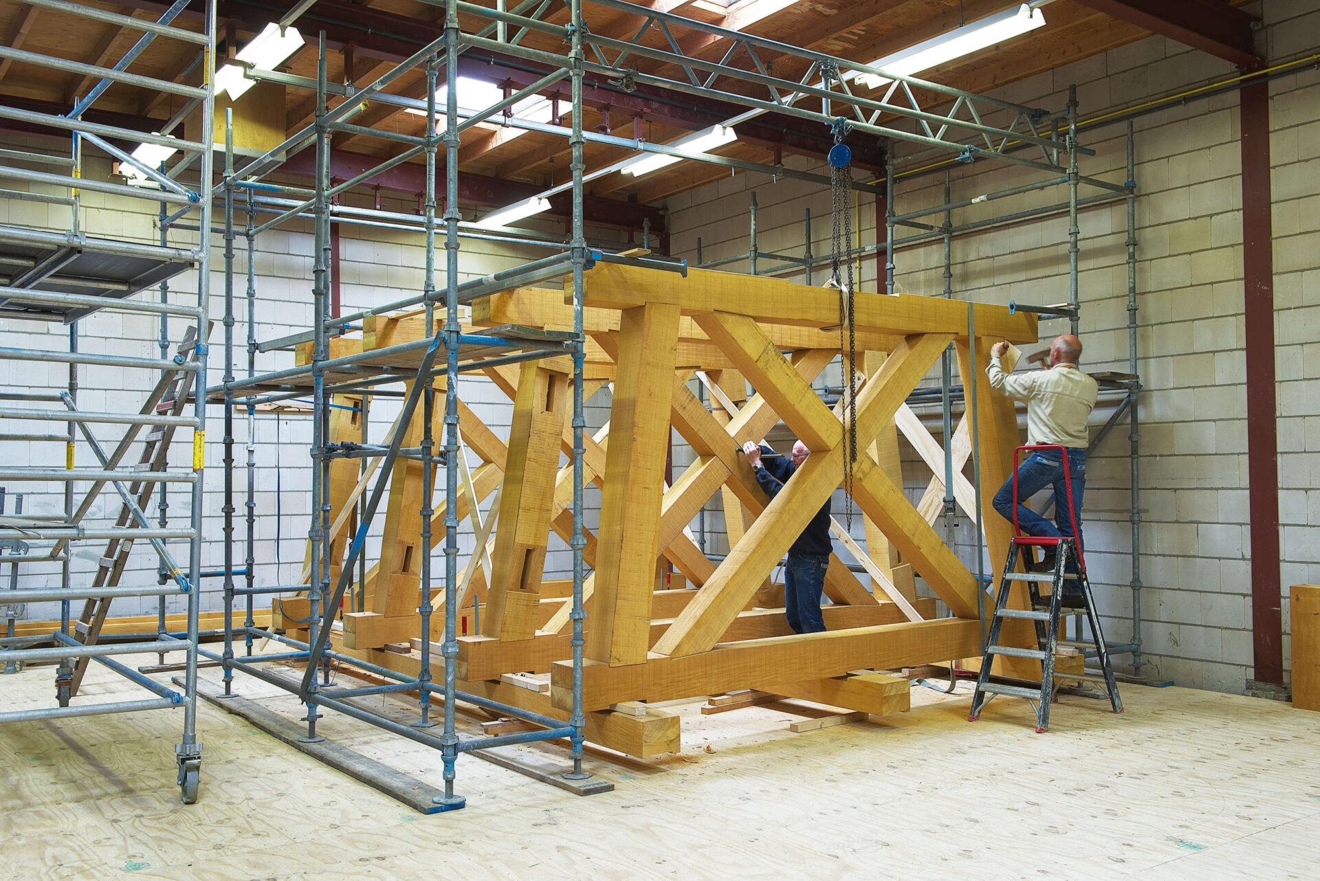 Medewerkers van Van Dinther aan het werk aan een houten constructie in de timmerwerkplaats
