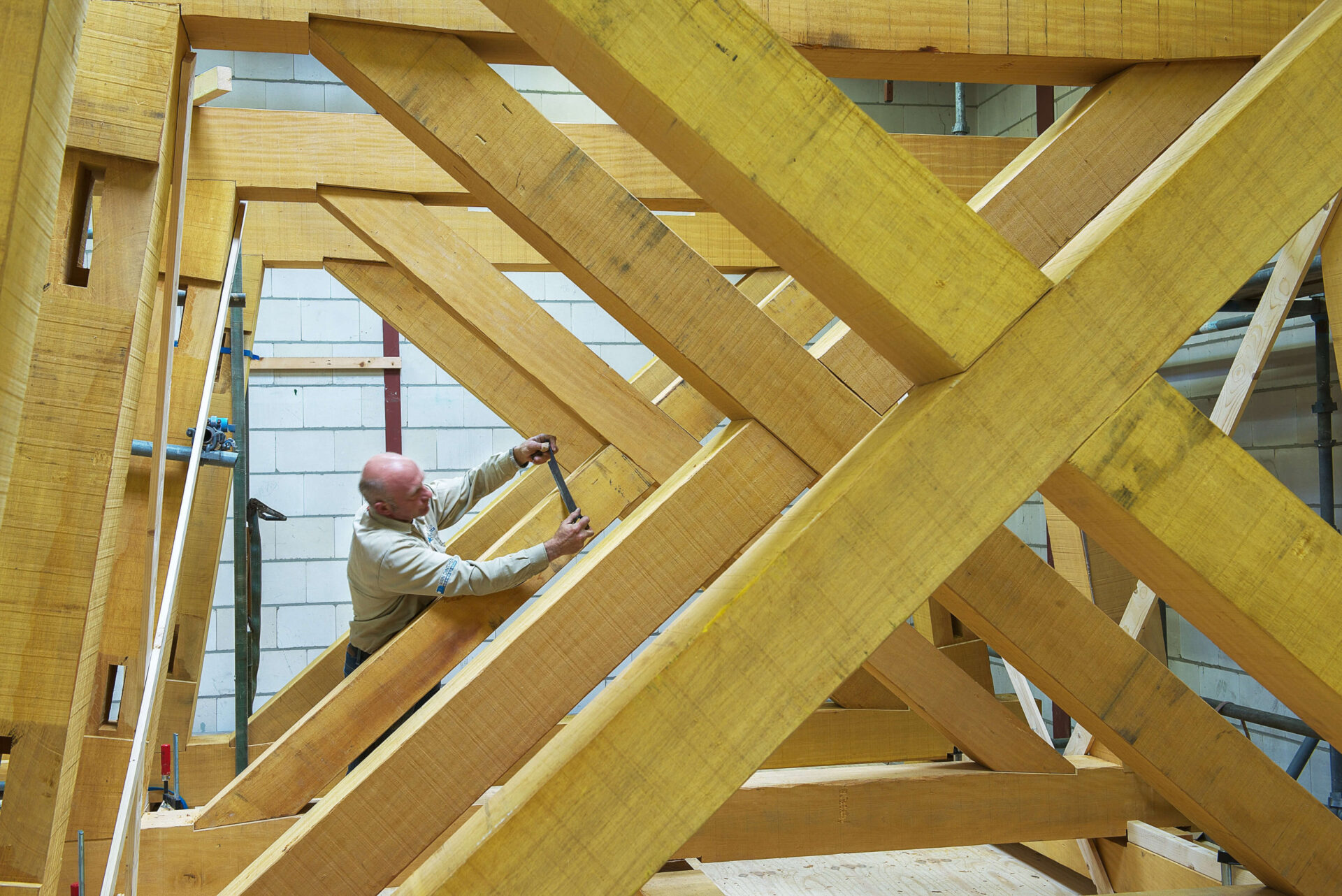 Medewerker van Van Dinther aan het werk aan een houten constructie in de timmerwerkplaats