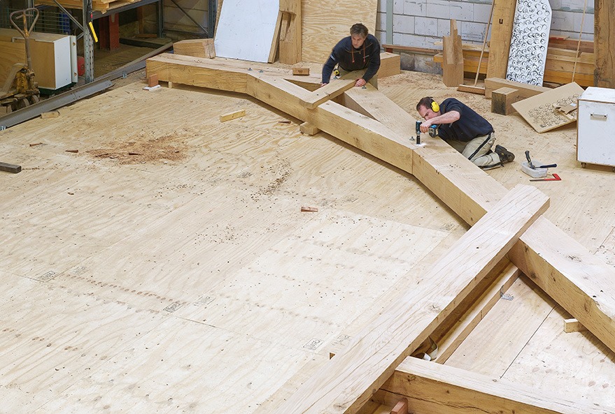Medewerkers van Van Dinther aan het werk aan een houten constructie in de timmerwerkplaats