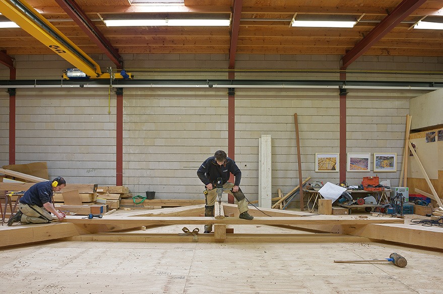 Medewerker van Van Dinther aan het werk aan een houten constructie in de timmerwerkplaats